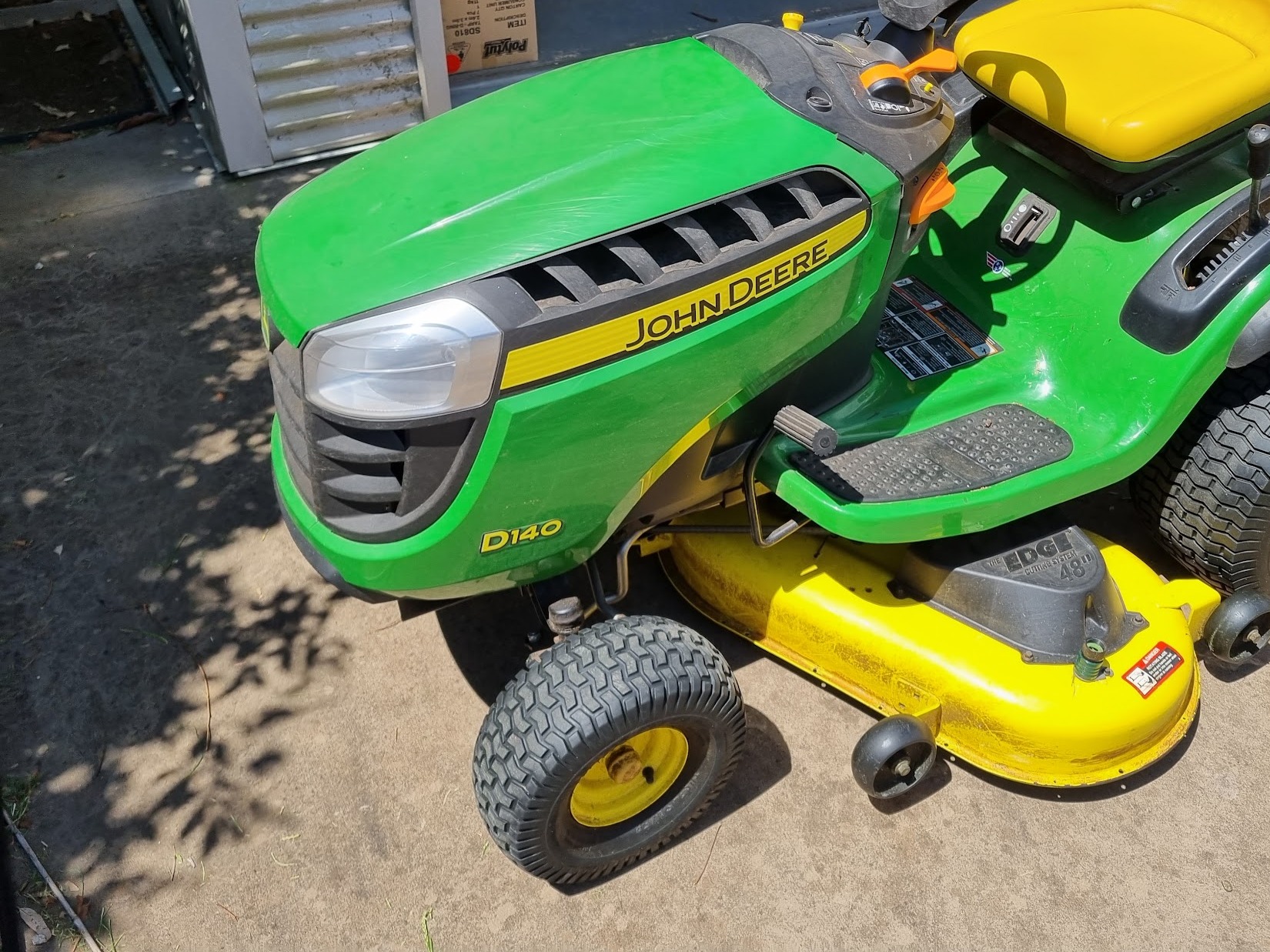 A John Deere D140 ride-on mower with its 48 inch deck, ready to go back